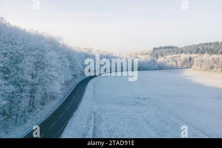 Une vue panoramique en hiver d'une route sinueuse traversant une forêt enneigée Banque D'Images