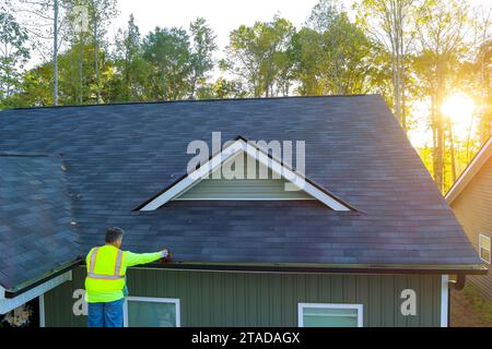 Le travailleur nettoie le drain bouché de gouttière de toit de la saleté, des débris, des feuilles tombées qui se sont accumulées Banque D'Images
