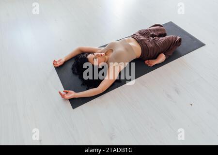 Belle femme bouclé sportive faisant des exercices de fitness yoga asana sur le sol Banque D'Images