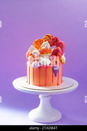 Gâteau à l'orange savoureux avec des bonbons sur fond violet Uni Banque D'Images