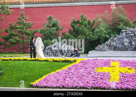 Photographe de mariage prenant une pause dans la photographie d'un couple nouvellement marié dans les Jardins olympiques, Pékin, Chine Banque D'Images