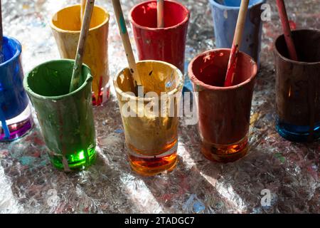 Verres et pinceaux utilisés pour peindre avec des pinceaux en eux Banque D'Images