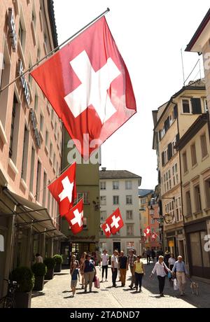 Zurich, Suisse - 03 juin 2017 : personnes dans la rue de Zurich décorées avec des drapeaux de Suisse. Drapeaux suisses sur le bâtiment de façade dans histori Banque D'Images