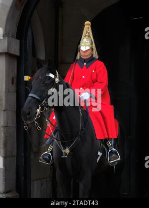 Soldat sauveteur revêtu de rouge avec cheval noir en service de garde à l'entrée de Horseguards Parade, Whitehall, Londres, Angleterre. Banque D'Images