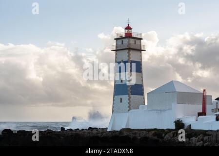 De grandes vagues s'écrasent dans les fondations du phare de Santa Marta dans le port de Cascais au Portugal Banque D'Images