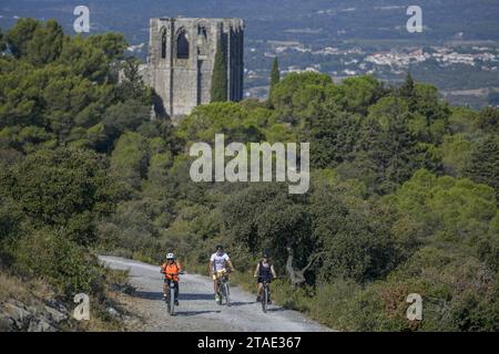 France, Hérault, Gigean, massif de la Gardiole, vététistes sur une route de gravier avec l'abbaye Saint-Félix de Montceau du 11e au 13e siècle Banque D'Images