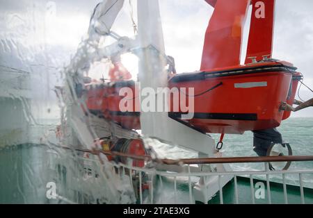 Bateau de sauvetage de ferry vu de l'intérieur du ferry regardant dehors sur une journée humide et orageuse Banque D'Images