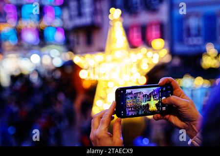 France, Haut Rhin, Colmar, marché de Noël, décorations et illuminations rue des marchands lors des fêtes de fin d'année, touriste prenant une photo des décorations de Noël de l'ancienne douane (Koïfhus) Banque D'Images