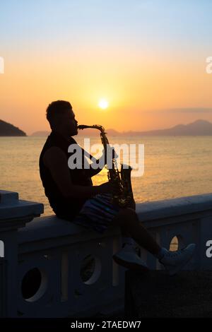 Santos, Brésil. 12 novembre 2023. Musicien jouant du saxophone au coucher du soleil à Santos. Banque D'Images