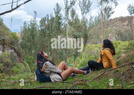 Deux amis latins se reposant d'une journée de randonnée et de sentiers en Équateur, assis les jambes écartées et regardant le ciel Banque D'Images