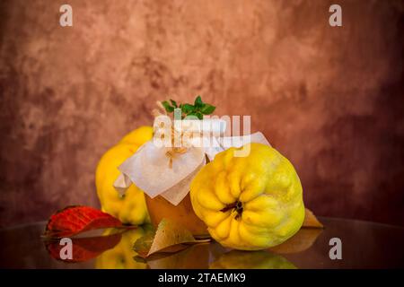 Fruits de coing mûrs avec de la confiture dans un bocal en verre sur une table en bois sombre. Recettes d'automne. Banque D'Images