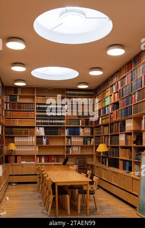 Une bibliothèque spacieuse avec étagères, plafonniers et une grande table avec plusieurs chaises, offrant un grand espace pour étudier ou lire Banque D'Images