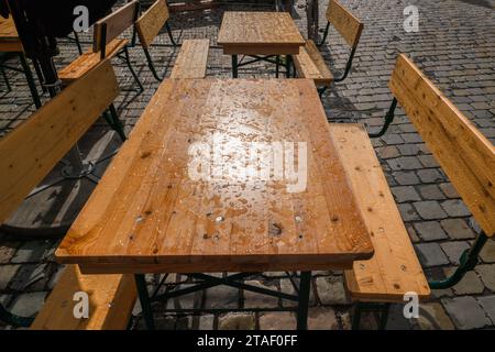 Tables et chaises en bois à l'extérieur dans le jardin sous la pluie. Banque D'Images