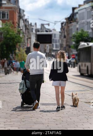 Un couple européen avec leur bébé dans une poussette et leur chien marchant dans les rues de la ville. Banque D'Images