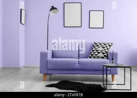 Intérieur du salon avec canapé lilas, table et lampadaire près du mur Banque D'Images