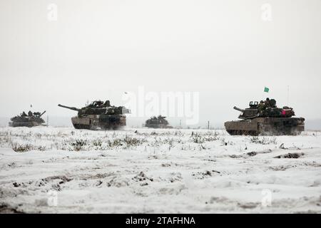 Les chars M1A2 Abrams de l'armée américaine de la compagnie Bravo, 3e bataillon, 67e régiment blindé, 2e brigade blindée, 3e division d'infanterie, effectuent un entraînement au tir réel au cours de l'exercice Ramming Bull organisé dans la zone d'entraînement de Pabrade, Lituanie, le 27 novembre 2023. Ramming Bull est une série d'exercices de tir réel menés par le groupement tactique de présence avancée renforcée de l'OTAN dirigé par l'Allemagne en Lituanie, destinés à tester la préparation, la cohésion et l'interopérabilité du groupement tactique. Les pays de l'OTAN participant à l'exercice comprenaient la Belgique, l'Allemagne, la Lituanie, les États-Unis et les pays-Bas Banque D'Images