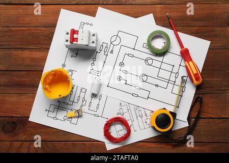 Schémas de câblage, tournevis et différents équipements d'électricien sur table en bois, pose à plat Banque D'Images