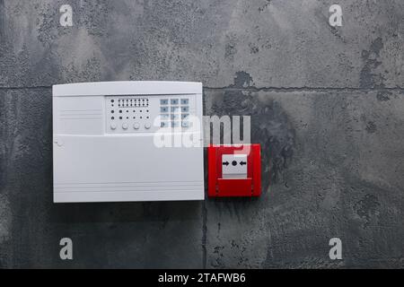 Bouton-poussoir d'alarme incendie et panneau de commande du système de sécurité de la maison sur le mur gris, espace pour le texte Banque D'Images