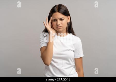 Portrait fatigué adolescente épuisée se sentant mal à la tête tenant la tempe par la main sur fond gris. Banque D'Images