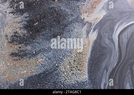 Fuite d'huile ou d'essence d'une voiture sur l'asphalte dans le stationnement sous la forme d'une tache de texture de marbre Banque D'Images