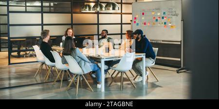 Divers groupes de professionnels participent à une discussion productive et à une séance de remue-méninges dans une salle de conseil. L'équipe, composée à la fois d'hommes et de femmes, Banque D'Images