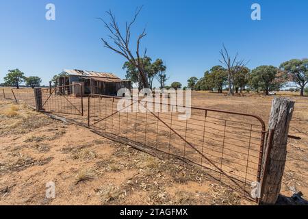 Un hangar de ferme abandonné derrière une porte de ferme rouillée sur des terres agricoles à Campbells Forest dans le centre du Victoria, en Australie Banque D'Images