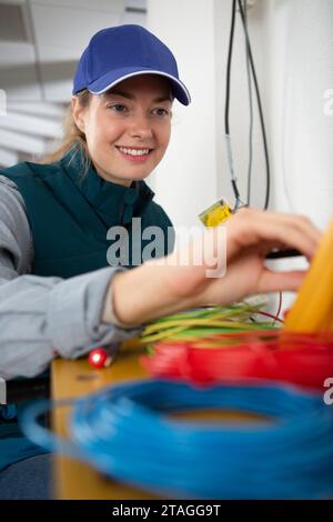 électricien féminin travaillant avec des câbles à l'intérieur Banque D'Images