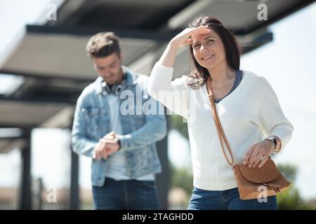 la femme attendant les transports publics protège les yeux du soleil Banque D'Images