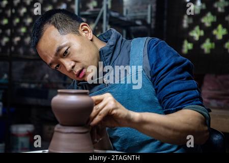 (231201) -- CHONGQING, 1 déc. 2023 (Xinhua) -- Guan Yongshuang réalise une œuvre d'art en poterie dans son atelier du district de Rongchang à Chongqing, dans le sud-ouest de la Chine, le 14 novembre 2023. Liang Xiancai, 73 ans, est un héritier de l'artisanat de poterie de Rongchang, un patrimoine culturel immatériel en Chine. Malgré la tendance à la mécanisation, à l'automatisation et à la production de poterie à grande échelle, il maintient fermement la tradition de la poterie manuelle. Guan Yongshuang, 32 ans, est diplômé de l'Institut des Beaux-Arts du Sichuan avec une majeure en art potier Il étudie la culture de la poterie depuis près de dix ans. Guan Banque D'Images