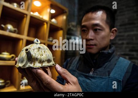 (231201) -- CHONGQING, 1 déc. 2023 (Xinhua) -- Guan Yongshuang vérifie une œuvre d'art en poterie dans son atelier du district de Rongchang à Chongqing, dans le sud-ouest de la Chine, le 14 novembre 2023. Liang Xiancai, 73 ans, est un héritier de l'artisanat de poterie de Rongchang, un patrimoine culturel immatériel en Chine. Malgré la tendance à la mécanisation, à l'automatisation et à la production de poterie à grande échelle, il maintient fermement la tradition de la poterie manuelle. Guan Yongshuang, 32 ans, est diplômé de l'Institut des Beaux-Arts du Sichuan avec une majeure en art potier Il étudie la culture de la poterie depuis près de dix ans. Guan Banque D'Images