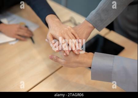 Image en gros plan d'un groupe de gens d'affaires divers se mettent les mains ensemble au-dessus d'une table de réunion. travail d'équipe, courage, soutien, confiance, unité Banque D'Images