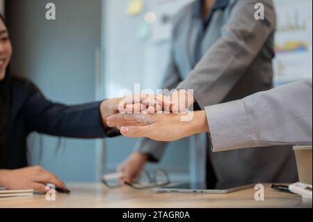 Image en gros plan d'un groupe de gens d'affaires divers se mettent les mains ensemble au-dessus d'une table de réunion. travail d'équipe, courage, soutien, confiance, unité Banque D'Images