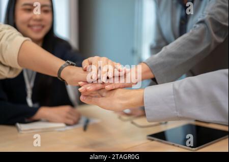 Image en gros plan d'un groupe de gens d'affaires divers se mettent les mains ensemble au-dessus d'une table de réunion. travail d'équipe, courage, soutien, confiance, unité Banque D'Images