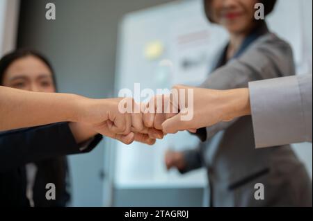 Image rapprochée de divers hommes d'affaires qui donnent un coup de poing à la réunion. team building, travail d'équipe, unité, collègues unissent leurs mains, motivant Banque D'Images