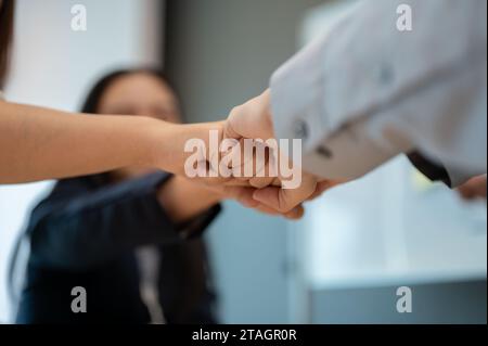 Image rapprochée de divers hommes d'affaires qui donnent un coup de poing à la réunion. team building, travail d'équipe, unité, collègues unissent leurs mains, motivant Banque D'Images