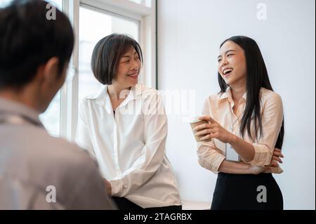 Groupe de collègues asiatiques heureux et divers hommes d'affaires aiment parler, rire et partager leurs idées pendant une pause café au bureau. Banque D'Images