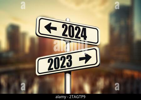 Les panneaux routiers indiquent le chemin vers la nouvelle année 2024 et l'ancienne année 2023 dans la ville moderne avec coucher de soleil, idée créative. Choisissez une nouvelle route, concept. Changer Banque D'Images