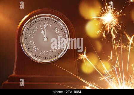 Horloge en bois antique change de 2023 à 2024 et étincelles de feux d'artifice pour les célébrations du nouvel an. Banque D'Images