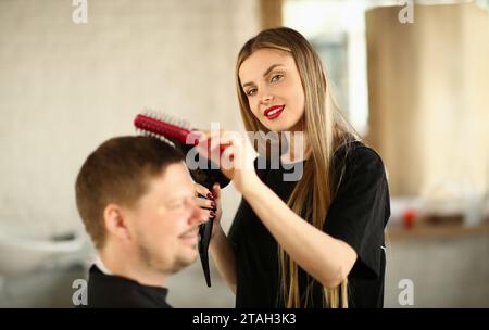 Femme en coiffure coiffure fait une coiffure avec sèche-cheveux pour les hommes client Banque D'Images