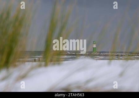 Rostock Warnemünde Strand, Deutschland 30. Novembre 2023 Der chapeau d'hiver Einzug gehalten. Spaziergänger gehen am Strand entlang. Zu sehen die Hafeneinfahrt mit dem grünen Molenfeuer im Vordergrund eine verschneite Düne Warnemünde Mecklenburg-Vorpommern *** Rostock Warnemünde Strand, Allemagne 30 novembre 2023 l'hiver est arrivé Walkers marcher le long de la plage l'entrée du port avec le feu vert de la jetée peut être vu au premier plan une dune enneigée Warnemünde Mecklenburg Vorpommern Copyright : xFotostandx/xVoelkerx crédit : Imago/Alamy Live News Banque D'Images