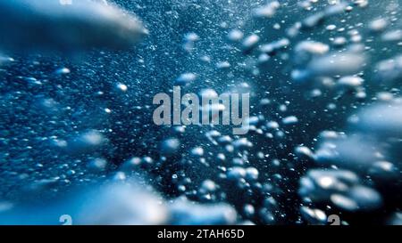 Bulles d'air ascendant du fond de l'océan à la surface de l'eau en mouvement lent, accompagnées par la libération d'air d'un plongeur. Abstrait et serein naturel Banque D'Images