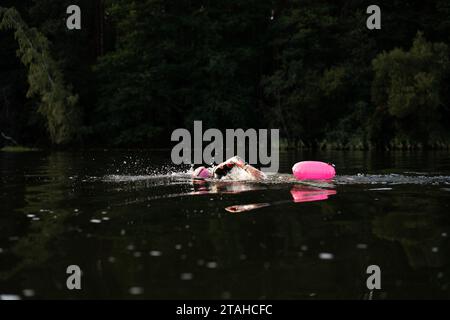 Nageur professionnel en combinaison nage en eau libre sur un lac. Banque D'Images