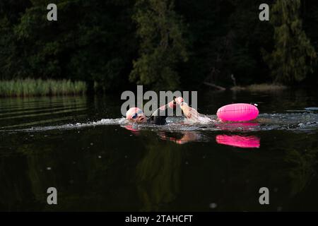 Nageur professionnel en combinaison nage en eau libre sur un lac. Banque D'Images