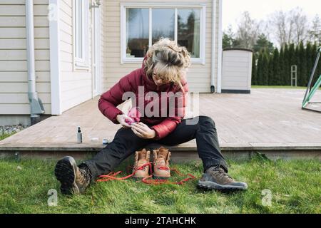 femme nettoyant ses bottes de randonnée dehors à la maison Banque D'Images