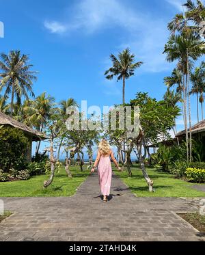 Femme en robe longue rouge marchant sur un chemin en bois sur tropical RE Banque D'Images