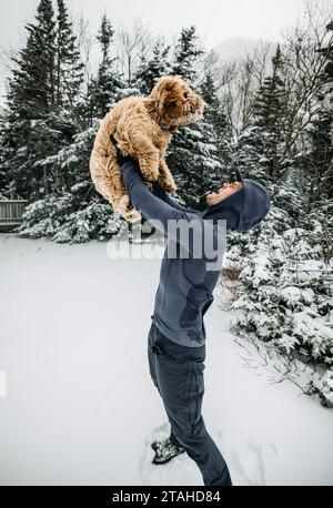 l'homme tient son chien avec joie tout en prenant la marche enneigée dans les bois Banque D'Images