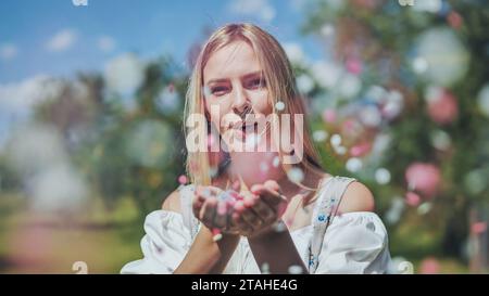 Une fille souffle des confettis en papier multicolores de ses mains. Banque D'Images