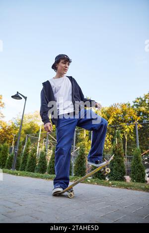 adolescent skateboarder équilibrant sur un skateboard à l'extérieur Banque D'Images