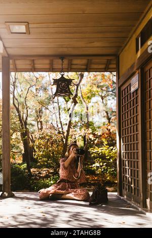 Femme prend des photos de bâtiment de style japonais à l'extérieur à l'automne Banque D'Images