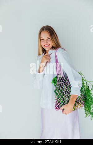 Femme avec des légumes frais de maille de sac pour manger le régime Banque D'Images